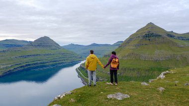 Çiftler nefes kesici Gonguturur Hvithamar Patikası 'nda el ele dururlar. Durgun sulara ve Faroe Adaları' nın yuvarlanan tepelerine bakarlar. Doğada bir huzur ve bağlantı anını yakalarlar..