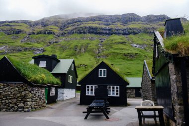 Faroe Adaları 'nın yemyeşil tepelerinde yuva yapmış, çimen çatıları olan büyüleyici siyah evler pitoresk bir köy oluşturuyor. Tjornuvik Köyü
