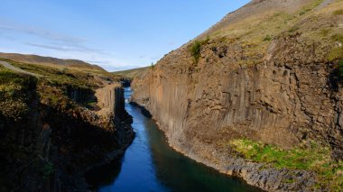 Studlagil Kanyonu İzlanda 'nın berrak suları boyunca görkemli bazalt sütunlar çarpıcı bir şekilde yükselir.