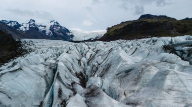 Svinafellsjokull Buzulu 'nun yüksek buz oluşumları İzlanda' nın engebeli zirvelerine çarpıcı bir şekilde açılır. Manzara doğal güzellikleri ve karmaşık dokuları sergiliyor..