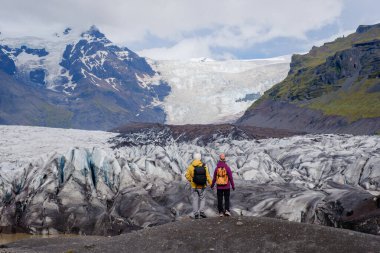 İki maceracı, engebeli dağlar ve eşsiz buz oluşumlarıyla çevrili muhteşem Svinafellsjokull Buzulu İzlanda 'nın önünde huşu içinde duruyor. Doğanın ihtişamı keşif ruhunu cezbeder..