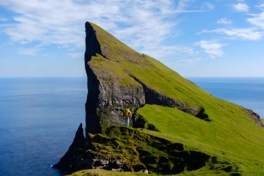 Faroe Adaları 'ndaki dramatik bir Mylingur uçurumunda durup nefes kesen kıyı şeridine bakan bir insan..