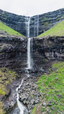 Fossa Şelaleleri, sarp kayalıklardan, Faroe Adaları 'ndaki yemyeşil tepelerle çevrili engebeli bir vadiye çarpıcı bir şekilde iner.. 