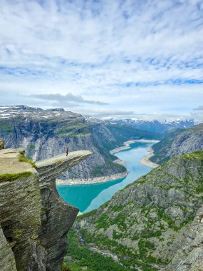 Cesur bir maceracı Norveç 'teki dramatik bir uçurumun kenarında yürüyor, nefes kesici fiyortlar ve canlı mavi sularla çevrili. Norveç 'te Trolltunga yürüyüşü