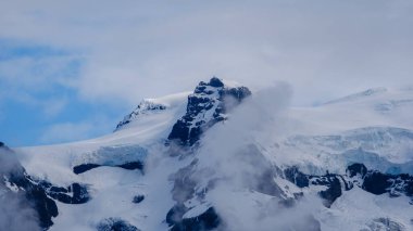 Svinafellsjokull Buzulu çarpıcı buz oluşumlarını ve dönen bulutlarla çevrili görkemli zirvelerini sergiliyor. İzlanda 'nın buzul manzarasının nefes kesici doğal güzelliğini tecrübe edin..