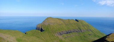 Faroe Adaları 'ndaki Kuzey Atlantik Okyanusu' ndan nefes kesici uçurumlar yükseliyor. Bereketli yeşillik, engebeli araziyi keşfeden yürüyüşçüler için sakin bir atmosfer yaratıyor..