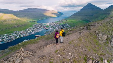 İki yürüyüşçü, dağlarla deniz arasında yuva yapmış Klaksvik kasabasının panoramik manzarasının keyfini çıkararak Faroe Adaları 'nın engebeli arazisini keşfeder. Doğada mükemmel bir macera güzellik..