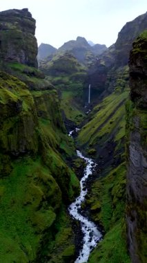İzlanda 'daki Mulagljufur Kanyonu' nun nefes kesici manzaralarını keşfedin. Yeşillik, sarp kayalıklar ve dingin nehir çarpıcı bir doğal manzara yaratır..