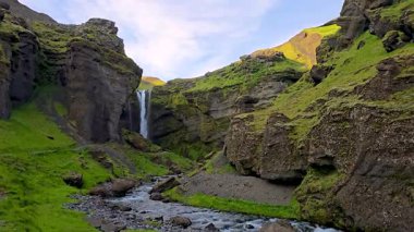 Sersemletici Kvernufoss Şelalesi 'ni keşfedin. Canlı yeşil yamaçları ve kıvrımlı bir nehri olan bir kanyona kurulmuş..