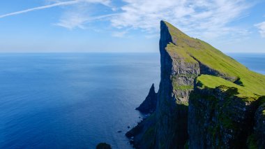 Mylingur uçurumu, sakin okyanus sularının üzerinde dramatik bir şekilde yükselir ve Faroe Adaları 'nın doğal güzelliğini gösterir. Bereketli yeşil yamaçlar, derin mavi denizle tezat oluşturarak çarpıcı bir manzara yaratıyor..