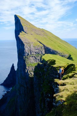 Görkemli Mylingur uçurumları, yemyeşil ve panoramik okyanus manzaralarıyla çevrili bir yürüyüşçünün kıyıda durduğu Faroe Adaları 'ndaki gökyüzüne doğru uzanıyor. Doğada sakin bir deneyim..