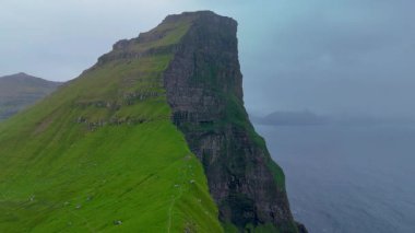Kalsos 'un dramatik uçurumlarının nefes kesici manzarası turkuaz sulardan keskin bir şekilde yükseliyor ve Faroe adalarının engebeli güzelliğini gözler önüne seriyor. Bu büyüleyici manzara huzur ve vahşilik yayar..