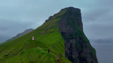 Kalsoy Adası 'nın çarpıcı uçurumları boyunca yürüyüş yapan engebeli arazi, dramatik gökyüzünün zeminine karşı bir deniz feneri ortaya çıkarıyor. Doğa güzelliği Faroe Adaları 'ndaki maceracıları cezbeder..