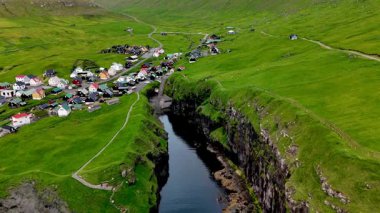 Büyüleyici Faroe Adaları 'ndaki büyüleyici Gjogv köyünü keşfedin. Bereketli yeşillik ve dingin sularla çevrili dramatik uçurumlara karşı kontrastlı evler..