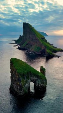 Gün batımında Atlantik Okyanusu 'ndan dramatik bir şekilde yükselen engebeli kaya oluşumlarının nefes kesici bir doğal manzara yarattığı Faroe Adaları' ndaki Drangarnir 'in büyüleyici uçurumlarını keşfedin..