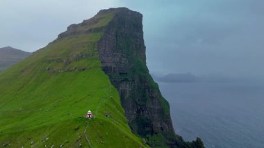 Benzersiz Faroe Adası olan Kalsoy 'un nefes kesici manzarasını tecrübe edin, büyüleyici yeşil uçurumlar ve tuhaf bir deniz feneri. Huzurlu bir atmosferde doğanın saf güzelliğini yakalamak için mükemmel..