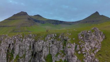 Faroe Adaları 'ndaki Gjogv' un büyüleyici güzelliğine tanık olun, yemyeşil kayalıklar bulutlu bir gökyüzü altında dramatik kaya oluşumlarıyla karşılaşıyor. Doğa meraklıları ve maceracılar için mükemmel..