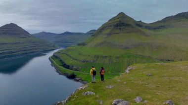Faroe Adaları 'ndaki Gonguturur Hvithamar Patikası' nın güzelliğini keşfedin. Orada sersemletici fiyortlara ve engebeli dağlara bakan yeşil tepeler üzerinde maceracılar durur..