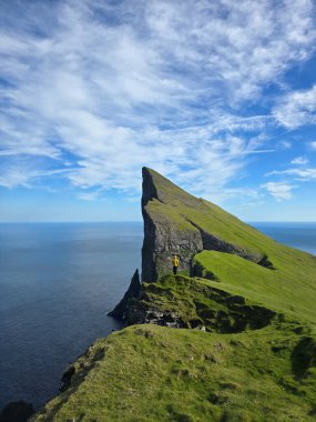Kaşifler Faroe Adaları 'ndaki büyüleyici uçurumların ve Mylingur yürüyüşünün tadını çıkarıyorlar. Bereketli yeşillik, derin mavi okyanus ve canlı gökyüzü ile güzel bir tezat oluşturuyor..