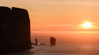 Günbatımı, Faroe Adaları 'ndaki ikonik Risin og Kellingin kaya oluşumlarına altın bir ışık saçar..