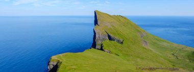 Yeşil Mylingur kayalıkları sakin mavi denize çarpıcı bir şekilde saplanarak, açık bir günde Faroe Adaları 'nın büyüleyici doğal güzelliğini gözler önüne serdi. Manzara keşfi ve hayranlığı davet eder..