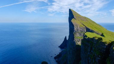 Mylingur uçurumu, sakin okyanus sularının üzerinde dramatik bir şekilde yükselir ve Faroe Adaları 'nın doğal güzelliğini gösterir. Bereketli yeşil yamaçlar, derin mavi denizle tezat oluşturarak çarpıcı bir manzara yaratıyor..