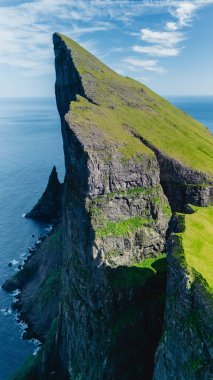 Faroe Adaları 'ndaki Mylingur kayalıkları göz kamaştırıcı doğal güzelliklerini canlı mavi gökyüzüne karşı sergiliyor. Yeşillik, engebeli kaya oluşumlarıyla çelişiyor. Her maceracıyı büyülüyor..