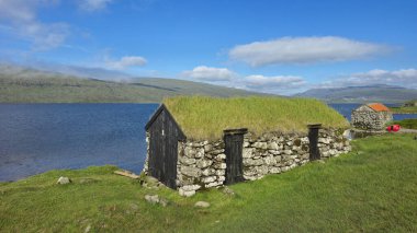 Faroe Adaları 'nın dingin sularının kıyısında büyüleyici, otlaklı bir kır evi huzur içinde duruyor. Bereketli yeşillik, açık mavi bir gökyüzünün altında, huzur ve keşfi davet ediyor..