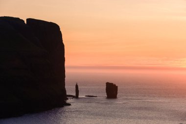Faroe Adaları 'nda, ikonik Risin og Kellingin kaya oluşumları okyanustan çarpıcı bir şekilde yükselir..