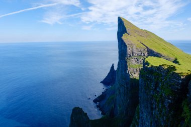 Faroe Adaları 'ndaki okyanus üzerinde nefes kesen Mylingur uçurumları yemyeşil manzaraları ve açık mavi gökyüzünü vurguluyor..