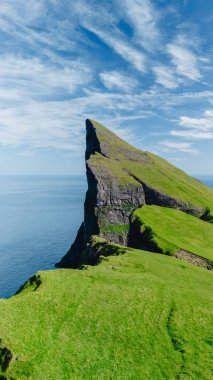 Güneşli bir günde, Kuzey Atlantik 'in sakin mavi suları üzerinde nefes kesici Mylingur uçurum oluşumları kulesi.