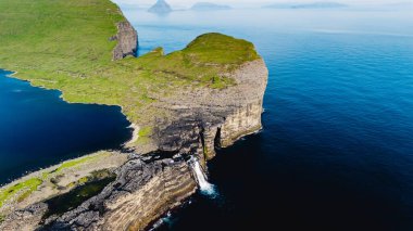 Faroe Adaları 'ndaki gök mavisi suların üzerinden dramatik uçurumlar yükselir ve şelale gibi akan bir şelale dingin körfeze akar. Yeşilli yeşil manzaralar büyüleyici doğal güzellikleri gözler önüne seriyor. Sorvagsvatn Gölü
