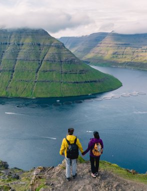 Göz kamaştırıcı Faroe Adaları 'ndaki Klakkur' da, iki çift el ele tutuşarak, aşağıdaki yemyeşil tepelere ve sakin sulara hayran kaldılar. Bu huzurlu ortam romantik maceranın özünü yansıtıyor..