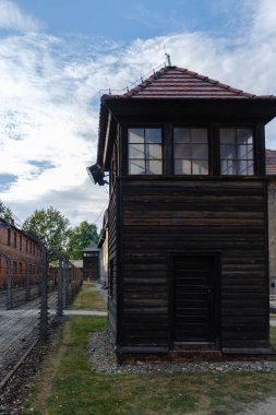 Fotoğraf, Polonya 'nın Auschwitz Birkenau kentindeki kamptan arta kalanlarla çevrili bir gözetleme kulesini yakalıyor. Parlak gökyüzü bu tarihi yerin ciddiyetini vurguluyor 