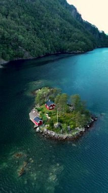 Norveç 'in sakin sularına yerleşen bu güzel adada büyüleyici kırmızı kulübeler, yemyeşil ağaçlar ve çarpıcı arka planlar bulunur. Huzur ve doğa severler için ideal bir yer..