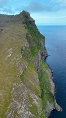 Faroe Adaları 'ndaki sakin denizden yükselen nefes kesici uçurum manzaralarını keşfedin. Bu sakin kıyı manzarası doğanın özünü Vidareidi 'deki en saf haliyle yakalıyor.
