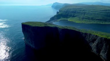 Faroe Adaları 'nın çarpıcı uçurumlarını ve sakin sularını keşfedin. Bu büyüleyici manzara, güneşin doğuşunda bu uzak yerin doğal güzelliğini ve engebeli arazisini gözler önüne seriyor. Sorvagsvatn Gölü