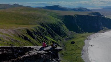 Norveç 'teki Matind Andoy' un nefes kesen uçurumları, iki maceraperestin yemyeşil ve kıyı şeridiyle çevrili doğal güzellikte dinlenmesi ve yıkanması ile dikkat çekici bir zemin sağlar..