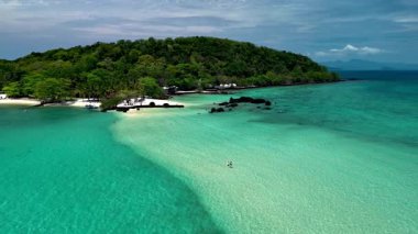 Tayland 'ın Turkuaz suları ve el değmemiş kumlu kıyılarıyla Koh Kham Adası' nın çarpıcı güzelliğini keşfedin. Birkaç beyaz erkek ve Asyalı kadın tatilde.