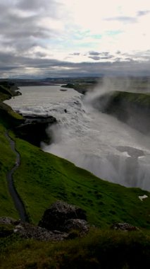 İzlanda 'daki nefes kesen Gullfoss şelalesini keşfedin. Suyun gür yeşillikler arasında engebeli uçurumlara çarpıcı bir şekilde düştüğü yeri. Doğanın bir mucizesi Güzellik bekliyor.