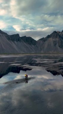 A stunning landscape showcases a serene lagoon reflecting dramatic mountains in Iceland. The calm waters create an idyllic setting for outdoor adventure Stokksnes Cape and Vestrahorn Mountain