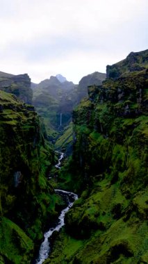 Explore the natural beauty of Mulagljufur Canyon in Iceland, featuring dramatic cliffs, vibrant greenery, and a winding river. The serene atmosphere offers a perfect escape for nature lovers.