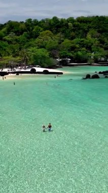 Discover the stunning turquoise waters and white sandy beaches of Koh Kham Island in Thailand. Visitors enjoy swimming, sunbathing, and exploring nature on this tropical paradise.