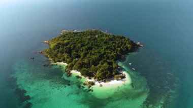 A breathtaking aerial perspective captures a tropical island in Thailand, surrounded by turquoise waters and vibrant plant life. Koh Munnork