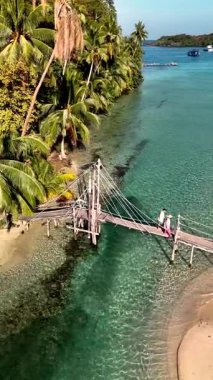 Discover the stunning views of Koh Kood in Thailand, featuring crystal-clear waters and vibrant greenery. A wooden bridge leads to a peaceful beach, inviting relaxation and exploration.