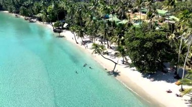 Visitors enjoy the tranquil beauty of Koh Kood in Thailand, relaxing on white sand beaches and swimming in clear turquoise waters under the warm sun. A perfect tropical paradise getaway awaits.
