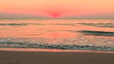 Experience a breathtaking sunset in Krabi Thailand, where warm hues fill the sky and gently reflect on the calm sea. Soft waves lap against the sandy shore, creating a serene atmosphere.