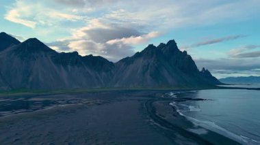 Explore the breathtaking beauty of Iceland, featuring towering mountains and a tranquil shoreline at dusk. Stokksnes Cape and Vestrahorn Mountain