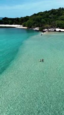 Koh Kham Island Thailand showcases stunning turquoise waters and soft sandy beaches. Visitors explore the calm, shallow waters, making it a perfect spot for relaxation and adventure.