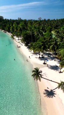 Glistening sands stretch along the shoreline of Koh Kood Thailand. Gentle waves lap against the beach, while palm trees sway softly in the breeze. Sunbathers enjoy the tranquil paradise.